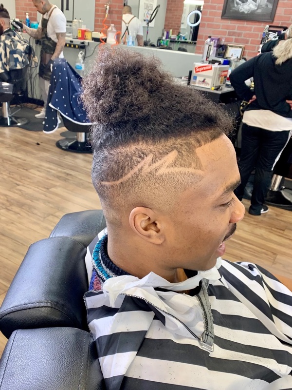 Burst fade with freestyle design and top knot
